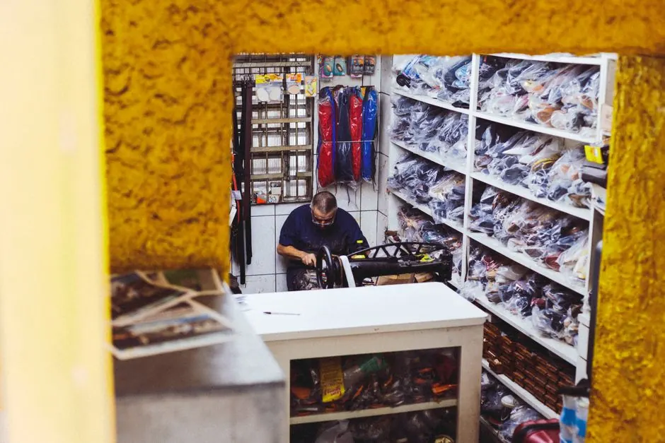 A man working in a small, cluttered storage room filled with tools and equipment.