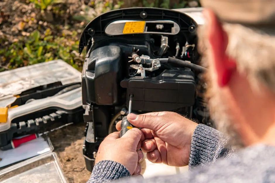 Close-up of a man working on outdoor equipment with a screwdriver, showcasing DIY repair skills.